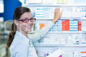 Pharmacist holding prescription while checking medicine in pharm
