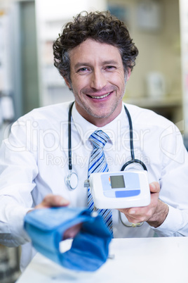 Pharmacist holding blood pressure monitor in pharmacy