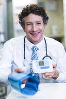 Pharmacist holding blood pressure monitor in pharmacy