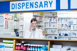 Pharmacist looking at medicine box while talking on phone