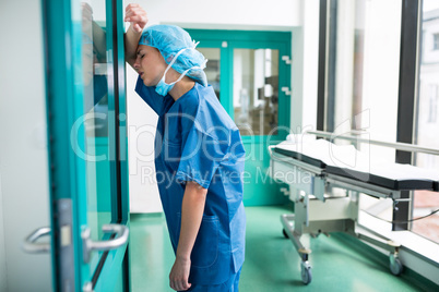 Sad surgeon leaning against the glass door