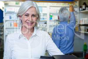 Pharmacist smiling and co-worker checking medicines