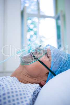 Patient wearing oxygen mask lying on hospital bed