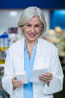 Pharmacist holding medicine and prescription in pharmacy