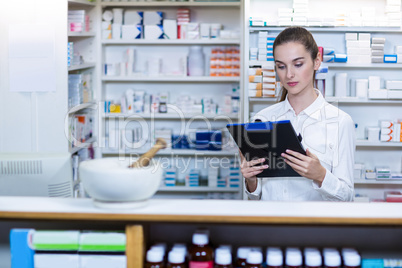 Pharmacist looking in clipboard at counter