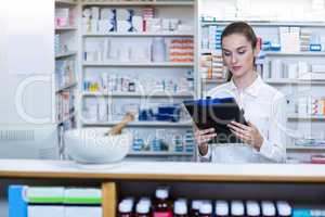 Pharmacist looking in clipboard at counter