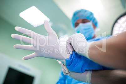 Nurse helping a surgeon in wearing surgical gloves