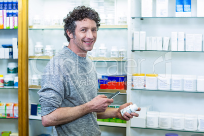 Customer using mobile phone with a bottle of drug in hand