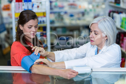 Pharmacist checking blood pressure of customer