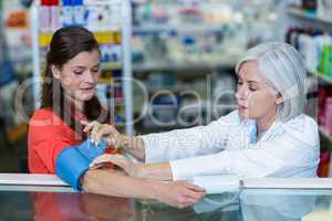 Pharmacist checking blood pressure of customer