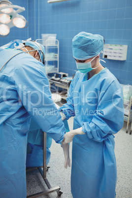 Nurse helping a surgeon in wearing surgical gloves