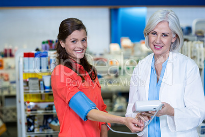 Pharmacist checking blood pressure of customer in pharmacy