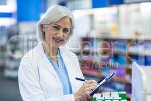 Pharmacist writing on clipboard in pharmacy