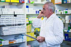 Pharmacist talking on mobile phone while checking medicines