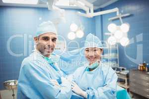 Portrait of surgeon and nurse standing with arms crossed in oper