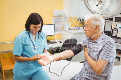 Female doctor checking blood pressure of patient