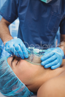Male surgeon putting an oxygen mask on patient