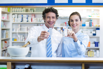Smiling pharmacist showing medicine in pharmacy