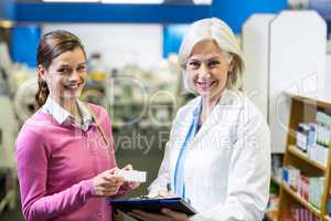 Pharmacist writing prescriptions for customer on clipboard in ph