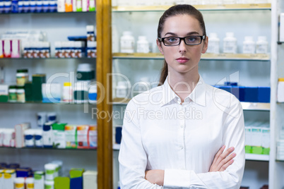 Pharmacist standing with arms crossed in pharmacy