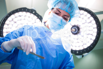 Female surgeon holding medical equipment in operating room