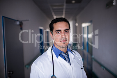 Confident doctor standing in hospital corridor