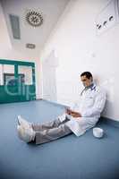 Doctor sitting on floor and using digital tablet in corridor