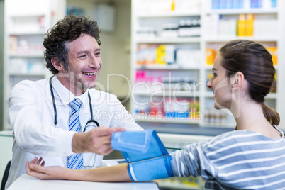 Pharmacist checking blood pressure of customer