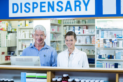 Smiling pharmacists standing at counter in pharmacy