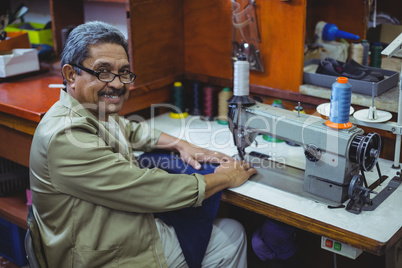 Portrait of smiling shoemaker using sewing machine
