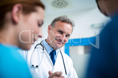 Portrait of smiling doctor standing with surgeons in corridor