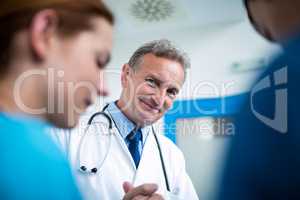 Portrait of smiling doctor standing with surgeons in corridor