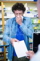 Customer sneezing while giving prescription to pharmacist