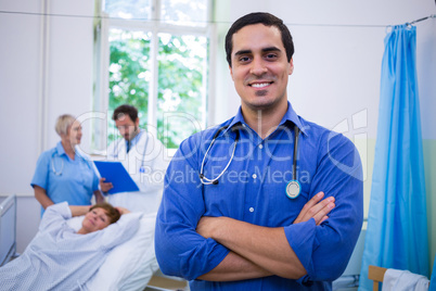 Smiling doctor standing with arms crossed in hospital