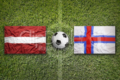 Latvia and Faroe islands flags on soccer field