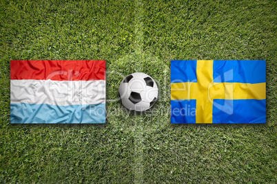 Luxembourg and Sweden flags on soccer field