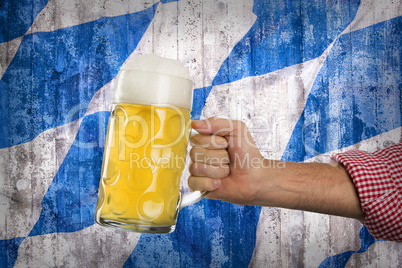 Man in traditional Bavarian shirt holds mug of beer