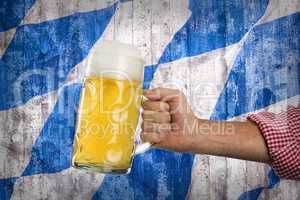 Man in traditional Bavarian shirt holds mug of beer