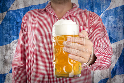 Man in traditional Bavarian shirt holds mug of beer