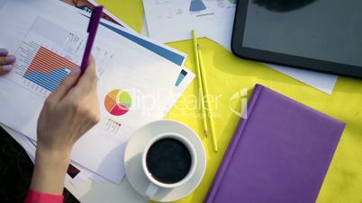 Human hands pointing with pen to paper charts