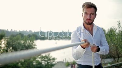 Young businessman pulling a rope outdoors