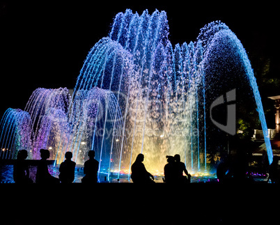 Night colored fountain with silhouettes of people.