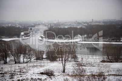 Winter landscape of snow-covered fields, trees and river in the early misty morning