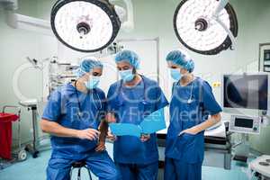 Surgeons discussing patient records in operation room