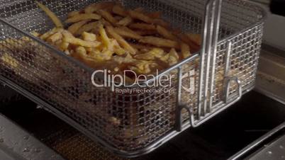 Inserting french fries into deep fryer. SLOG3, medium shot.