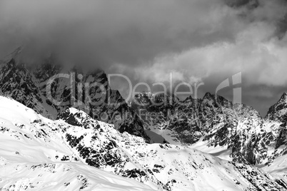 Black and white snowy rocks in clouds at sunny day