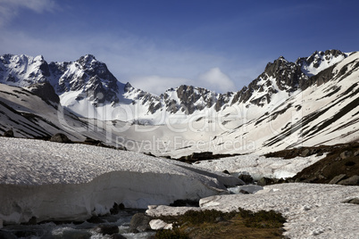 River with snow bridges in spring mountains at sun morning