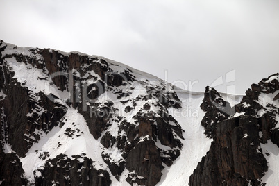 Rocks with snow cornice in gray day