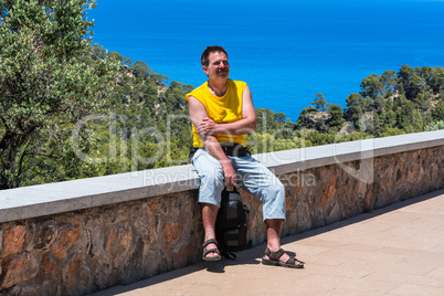 Mann auf Mauer im Hintergrund das Meer.