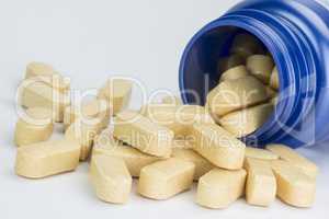 Yellow tablets from a blue medicine jar.